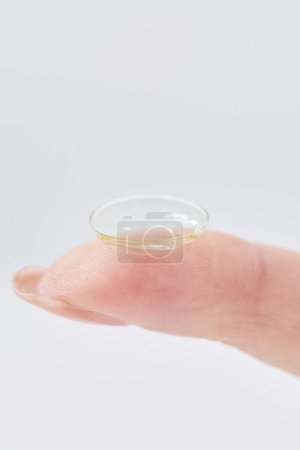woman's fingers with contact lenses and white background
