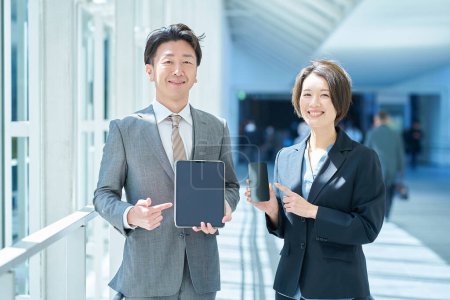 Ein Mann und eine Frau in Anzügen mit tragbaren digitalen Kommunikationsgeräten in der Hand