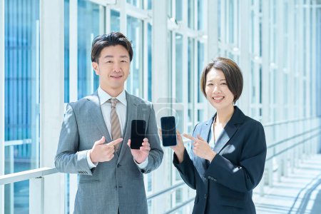 A man and a woman in suits holding portable digital communication devices in their hands