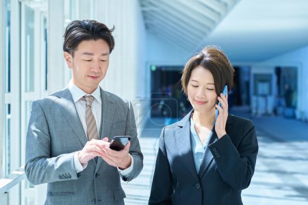 Un hombre y una mujer en trajes operan un teléfono inteligente con una sonrisa