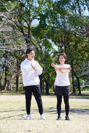 Man and woman doing warm-up exercises on fine day