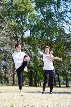 Man and woman doing warm-up exercises on fine day