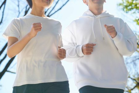 Man and woman running side by side outdoors on fine day