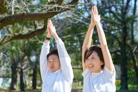 Man and woman doing yoga side by side outdoors on fine day