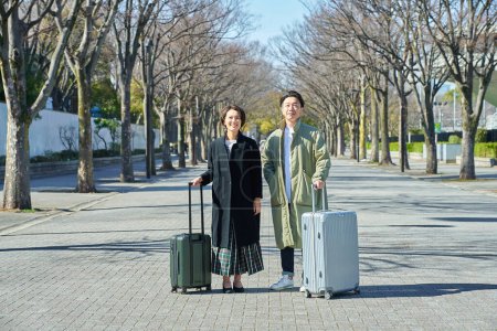 A man and a woman with suitcases smiling