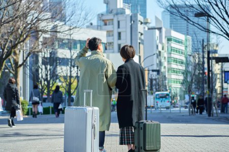 Rear view of a man and a woman with suitcases on the street