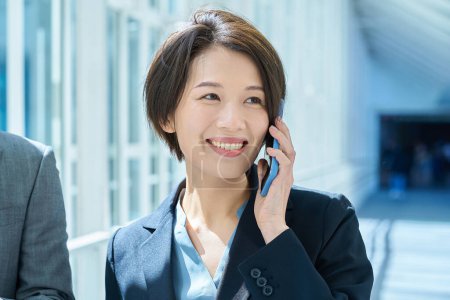 Téléchargez les photos : Une femme parle sur un smartphone avec un sourire - en image libre de droit