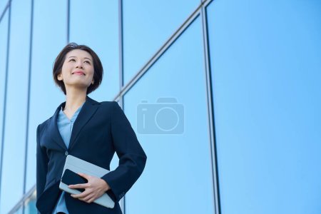 Geschäftsfrau im Anzug blickt nach oben in den Himmel