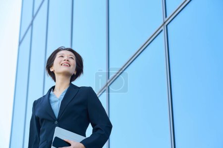 Mujer de negocios con un traje mirando al cielo al aire libre