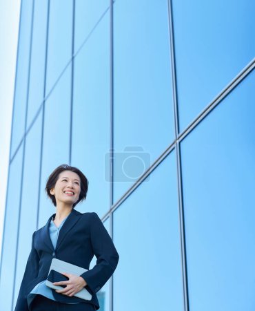 Mujer de negocios con un traje mirando al cielo al aire libre