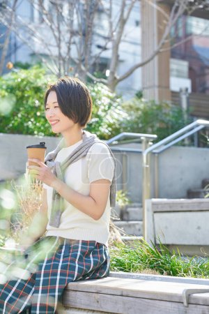 Woman looking relaxed while drinking coffee outdoors