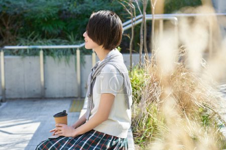Frau sieht beim Kaffeetrinken im Freien entspannt aus