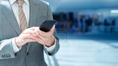Hand of a businessman operating a smartphone outdoors