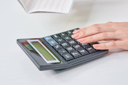 Una mujer sosteniendo una cuenta bancaria y usando una calculadora