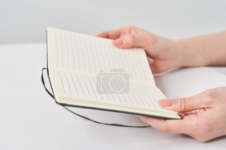 Hand of a woman holding a notepad and white background