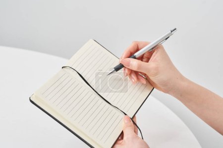 Hand of a woman holding a notepad and white background