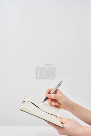 Hand einer Frau mit Notizblock und weißem Hintergrund