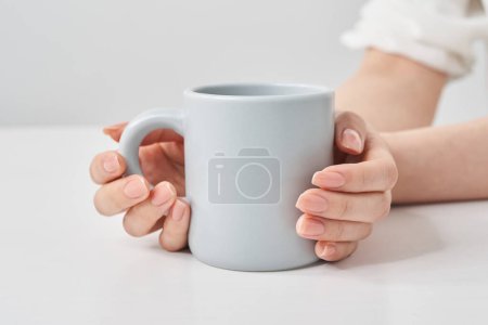 Woman's hand holding a mug and white background