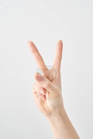 Close-up of a hand making the V sign and white background
