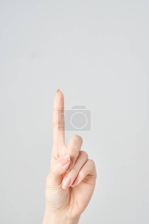 A woman's index finger pointing upwards and white background
