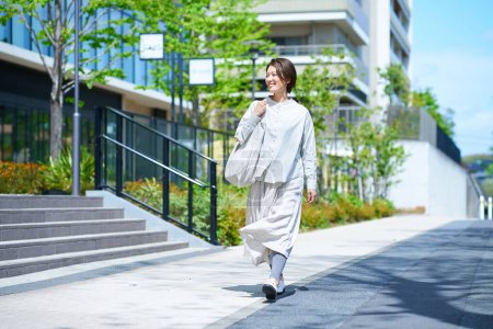 Eine Frau läuft an einem sonnigen Tag mit Einkaufstüten die Straße entlang