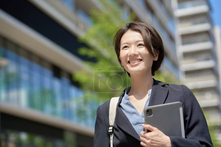 Femme d'affaires marchant dans la ville par une journée ensoleillée