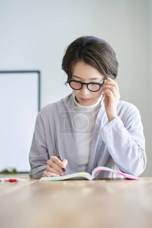 Eine Frau mittleren Alters lernt aus einem Lehrbuch