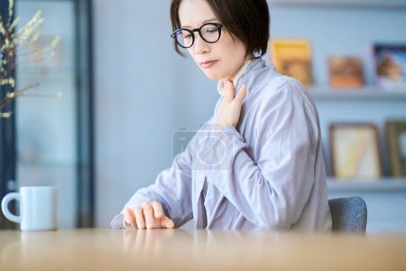 A woman who seems to feel discomfort in her throat in the room