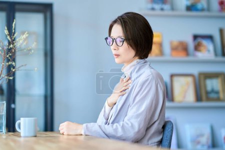 A woman who seems to feel discomfort in her throat in the room
