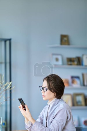 A woman operating a smartphone looking tired in the room