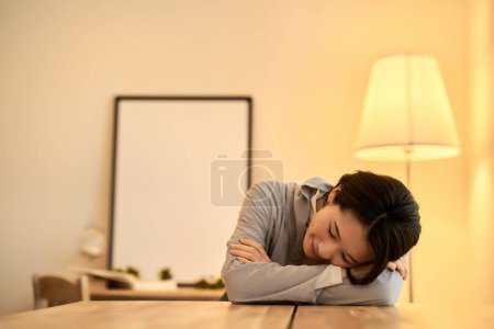 Photo for A middle-aged woman with a relaxed expression in a room with warm indoor lighting - Royalty Free Image