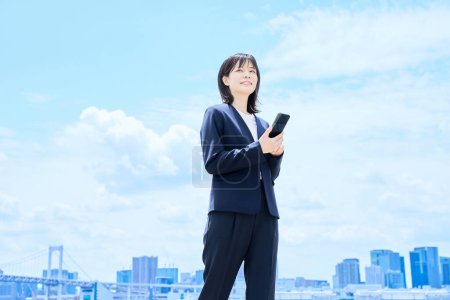 Eine junge Geschäftsfrau bedient ihr Smartphone im Freien