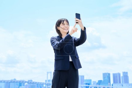 Eine junge Geschäftsfrau bedient ihr Smartphone im Freien