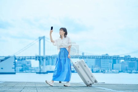 Young woman walking with suitcase outdoors