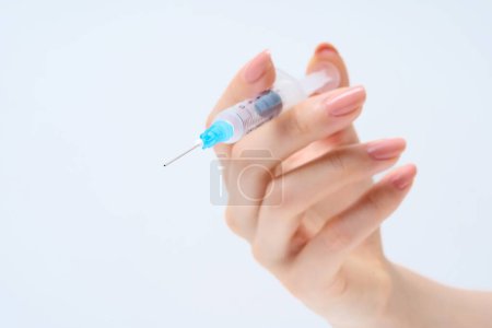 Woman's hand holding a syringe and White background