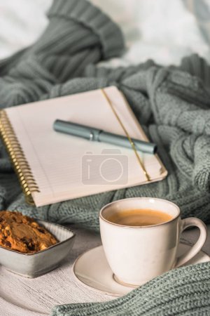 Foto de Una taza de café y galletas en una cama acogedora. Jersey de lana caliente para un acogedor fin de semana de otoño, desayuno en la cama, coffee break. Concepto Hygge - Imagen libre de derechos