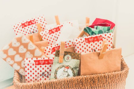 Photo for Handmade advent calendar with colorful paper bags and stickers in a woven basket - Royalty Free Image