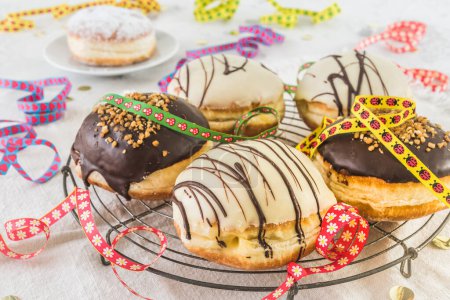 Téléchargez les photos : Traditional german Berliner pastries glazed with dark and white chocolate and hazelnut brittle, decorated for party or carnival - en image libre de droit