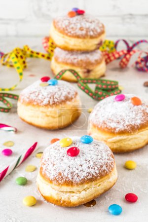 Téléchargez les photos : Donuts levés au sucre en poudre de carnaval avec banderoles en papier, confettis et fèves de chocolat sur fond blanc, vertical - en image libre de droit