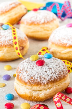Téléchargez les photos : Carnival powdered sugar raised donuts with paper streamers, confetti and chocolate beans, vertical - en image libre de droit