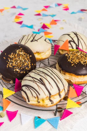Téléchargez les photos : Traditional german Berliner pastries glazed with dark and white chocolate and hazelnut brittle, decorated for party or carnival, vertical - en image libre de droit