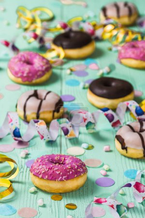 Téléchargez les photos : Donuts, Berlinois, Krapfen avec banderoles et confettis. Image colorée de carnaval, anniversaire et fasching, fond vert, vertical - en image libre de droit
