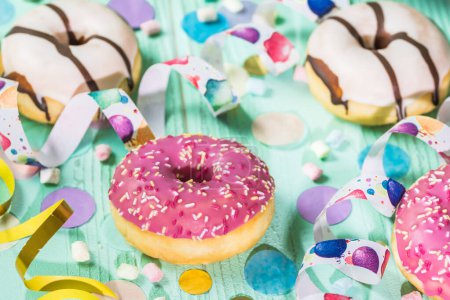 Téléchargez les photos : Donuts, Berlinois, Krapfen avec banderoles et confettis. Image colorée de carnaval, anniversaire et fasching, fond vert - en image libre de droit