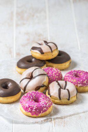 Téléchargez les photos : Colorful Donuts, Berliner, Krapfen with sugar icing and chocolate on white wooden background, vertical with copy space - en image libre de droit