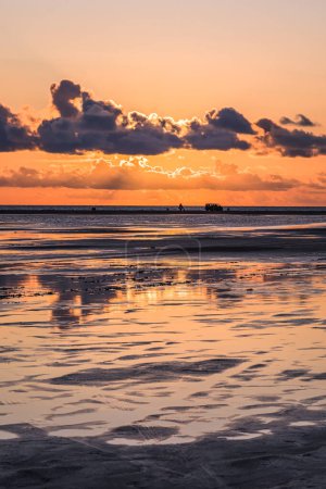 Photo for Sunset on a cloudy colorful sky over the North Sea in Denmark with high reflection in the water, vertical - Royalty Free Image