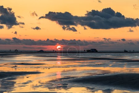 Téléchargez les photos : Coucher de soleil sur un ciel nuageux et coloré au-dessus de la mer du Nord au Danemark avec une réflexion élevée dans l'eau - en image libre de droit