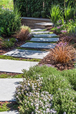Foto de Camino con grandes losas de piedra a través de un jardín bellamente plantado, vertical - Imagen libre de derechos