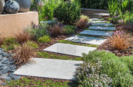 Téléchargez les photos : Chemin avec de grandes dalles de pierre à travers un jardin magnifiquement planté - en image libre de droit