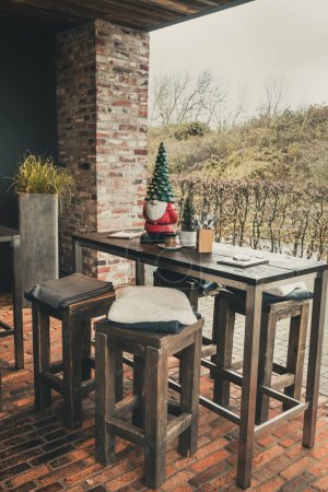 Photo for Outside of a cafe with wooden table and barstools and christmas decoration - Royalty Free Image
