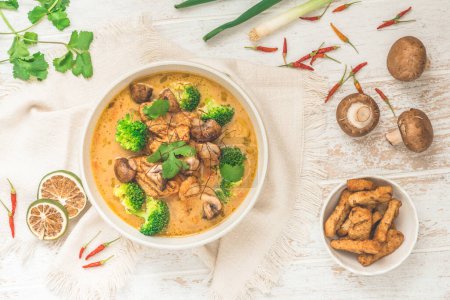 Schüssel mit Tom Kha Gai Suppe mit verschiedenen Gemüsesorten, von oben